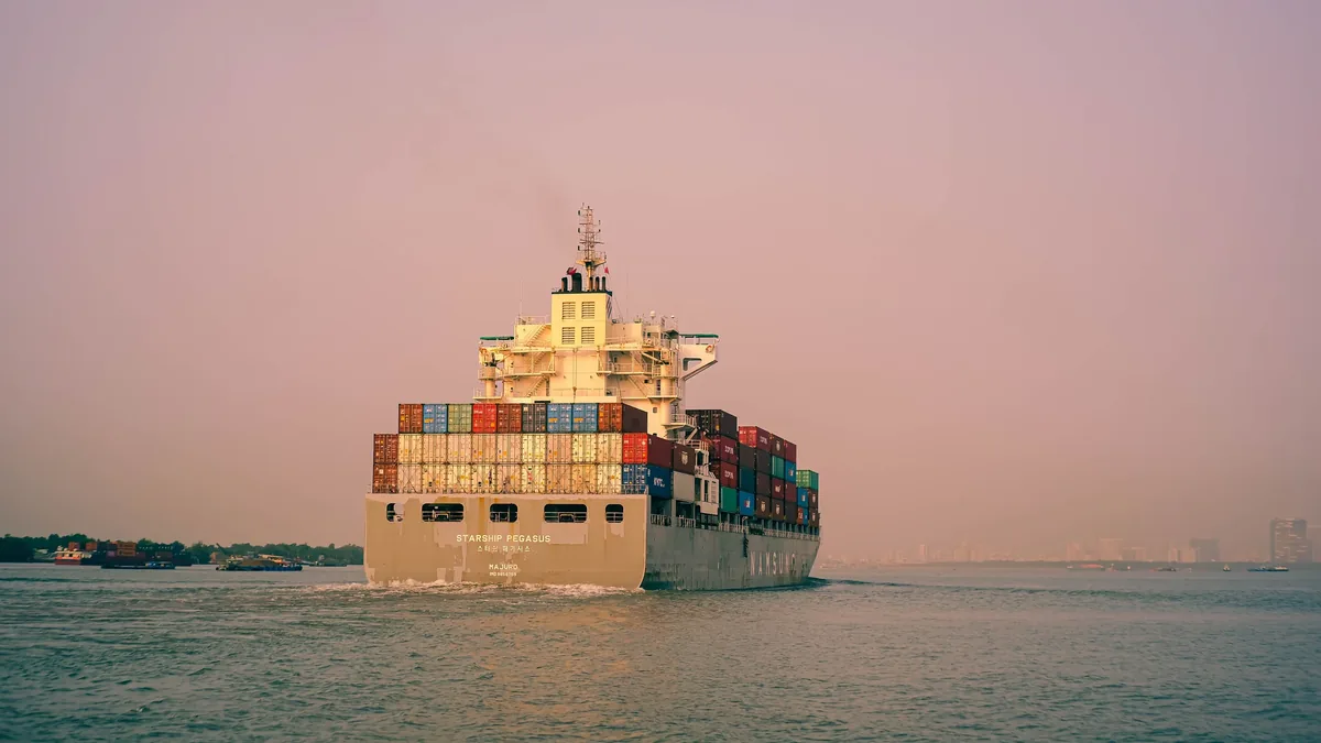 A large cargo ship with many shipping containers on it, sailing on a body of water.